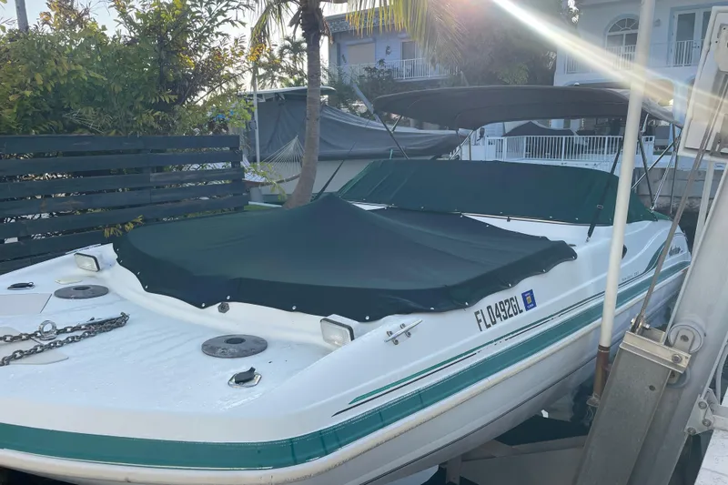 Slide: The Image of 2000 Hurricane SunDeck 237 OB boat docked with cover, surrounded by tropical foliage. - 5