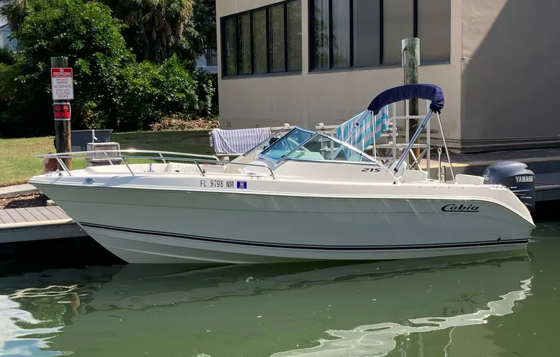 The Image of 2007 Cobia 215 Dual Console boat docked by a building, featuring a Yamaha outboard motor. - 0