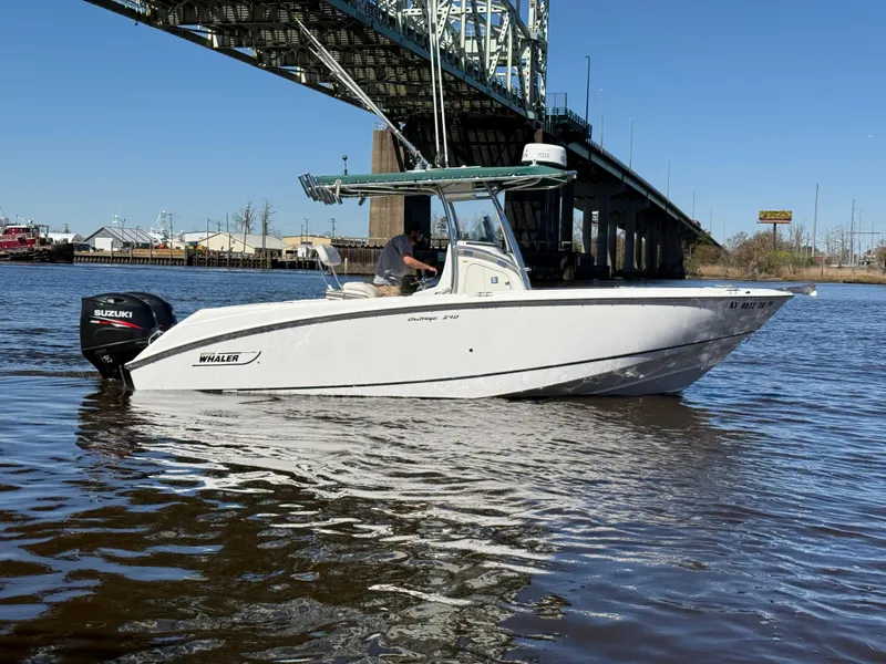 Slide: The Image of 2003 Boston Whaler 240 Outrage boat on water near a bridge. - 0
