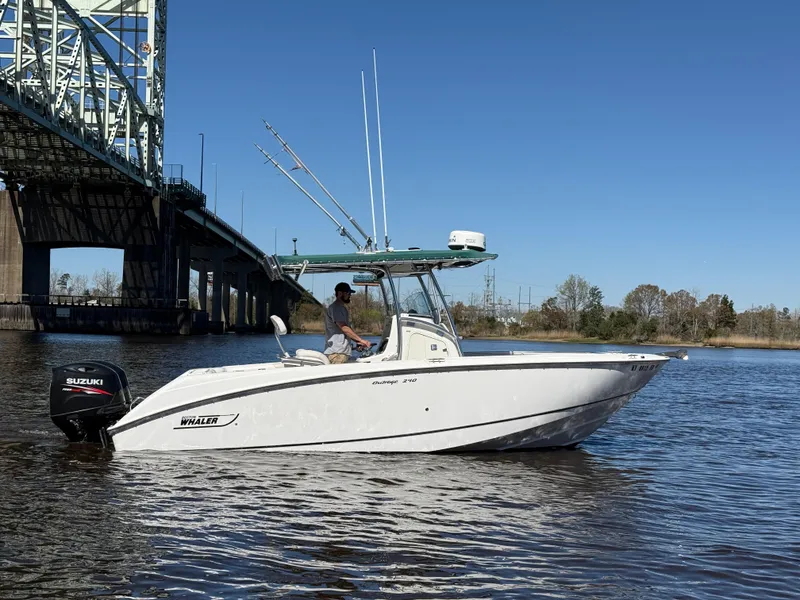 Slide: The Image of 2003 Boston Whaler 240 Outrage boat on water near a bridge, clear sky. - 1