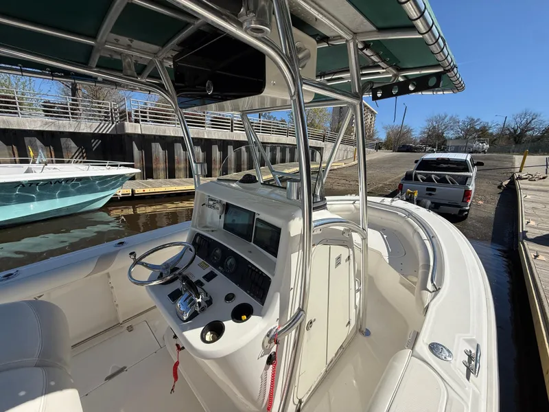 Slide: The Image of 2003 Boston Whaler 240 Outrage boat with console and seating, docked near a truck. - 16