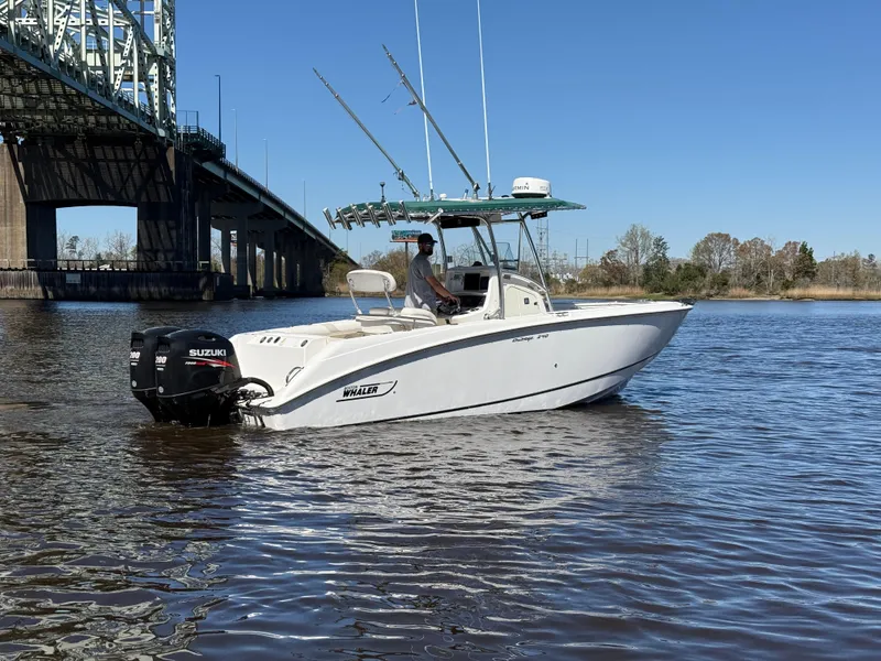 Slide: The Image of 2003 Boston Whaler 240 Outrage boat on water near a bridge, clear blue sky. - 2