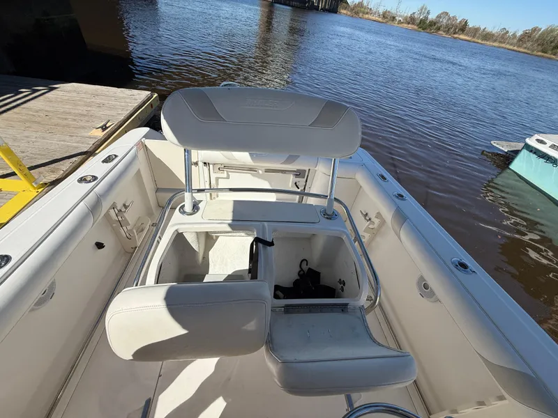 Slide: The Image of 2003 Boston Whaler 240 Outrage boat interior with seating and storage, docked by a river. - 25