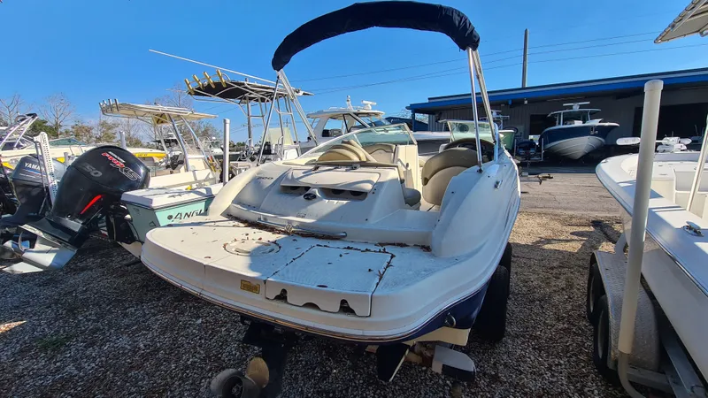 Slide: The Image of 2005 Sea Ray 200 Sundeck boat with seating, parked in a marina under clear skies. - 17