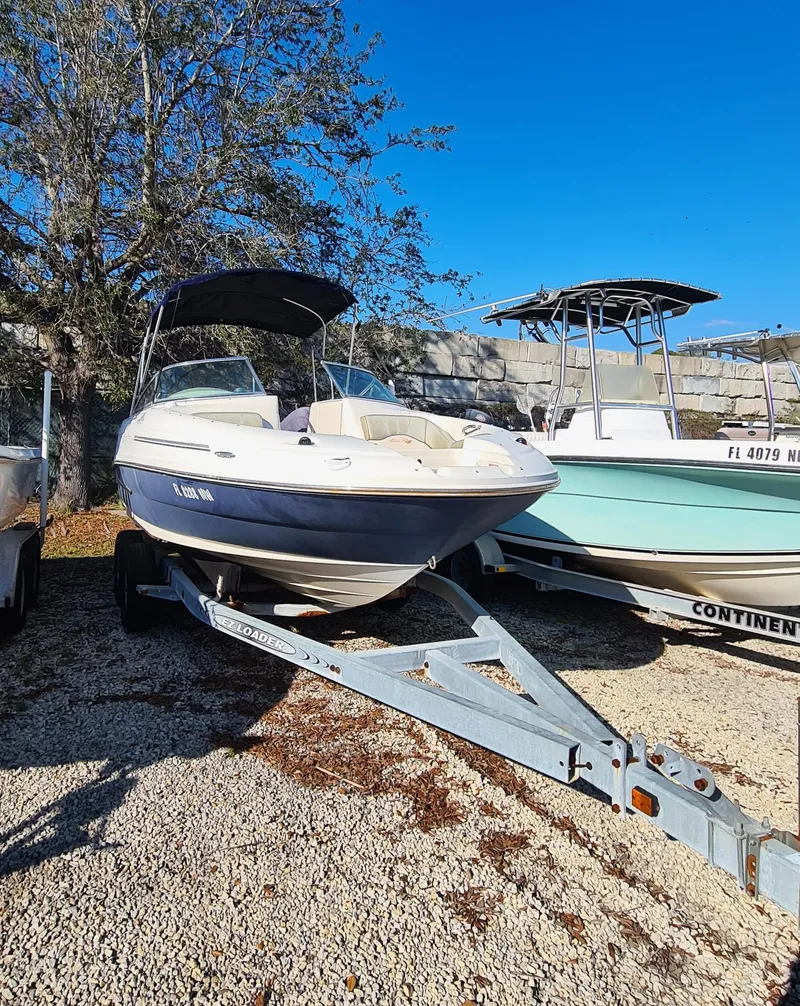 Slide: The Image of 2005 Sea Ray 200 Sundeck boat on trailer, parked outdoors under clear blue sky. - 19