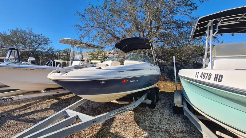Slide: The Image of 2005 Sea Ray 200 Sundeck boat on trailer, parked outdoors under clear blue sky. - 21