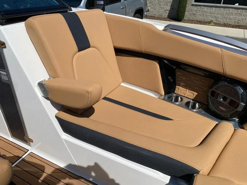 Slide: The Image of 2021 MasterCraft X24 boat interior with tan and black seating, cup holders, and speaker. - 12