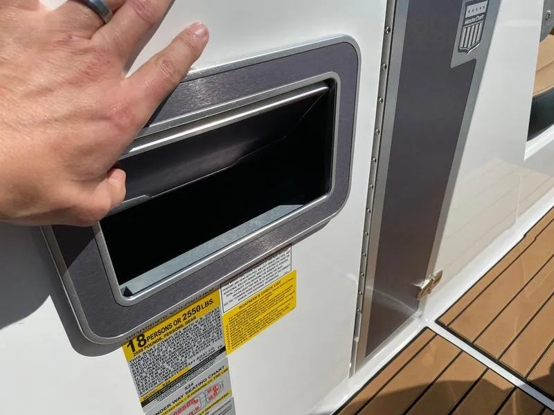 Slide: The Image of Hand opening storage compartment on 2021 MasterCraft X24 boat deck. - 14