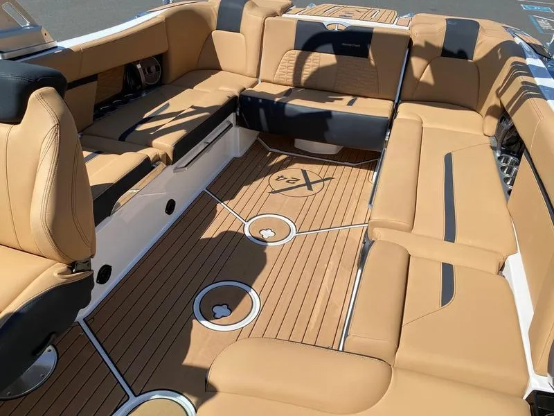 Slide: The Image of 2021 MasterCraft X24 boat interior with tan and black seating, teak flooring. - 15