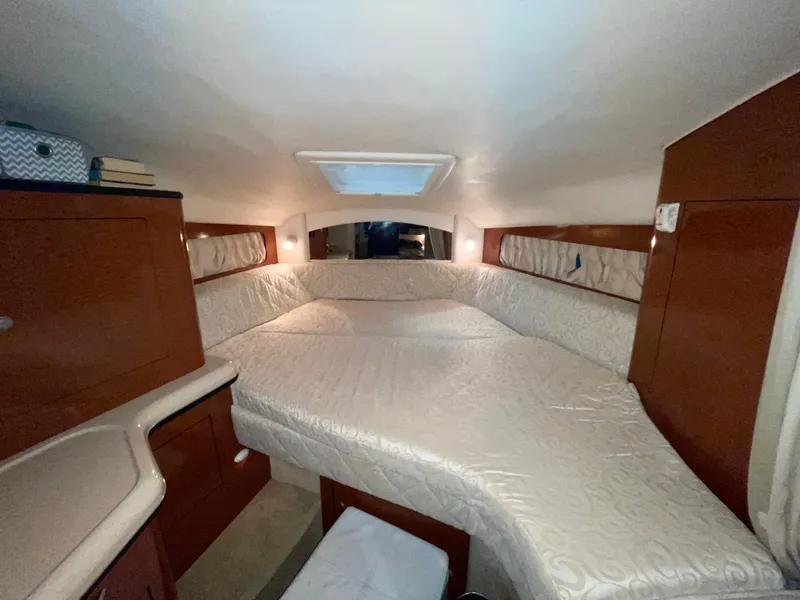 Slide: The Image of 2005 Sea Ray 300 Sundancer cabin interior with cozy bed and wooden cabinetry. - 28