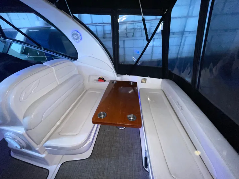 Slide: The Image of 2005 Sea Ray 300 Sundancer interior with white seating and wooden table. - 6