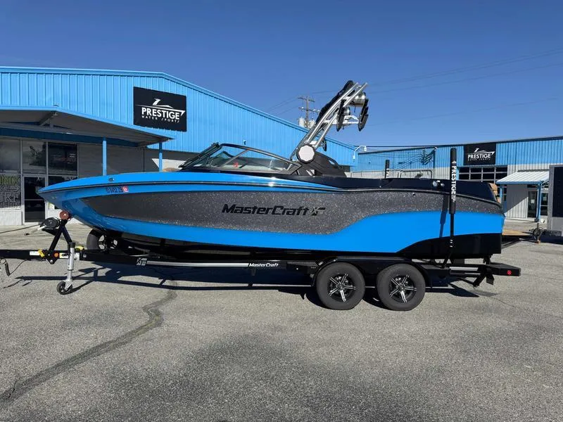 Slide: The Image of 2022 MasterCraft XT23 boat in blue and black on a trailer outside a dealership. - 1