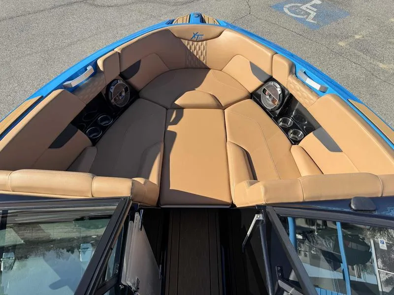 Slide: The Image of 2022 MasterCraft XT23 boat interior with tan seating and blue accents. - 13