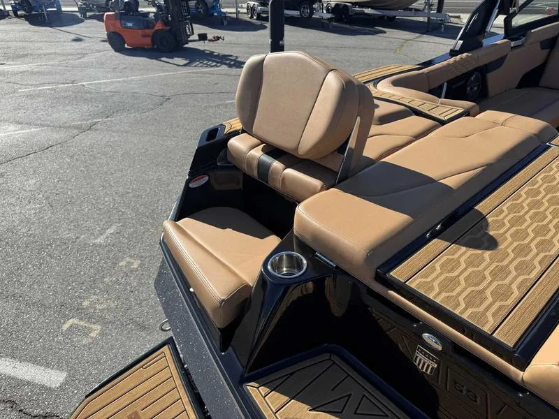 Slide: The Image of 2022 MasterCraft XT23 boat interior with tan seating and cup holder, parked outdoors. - 18