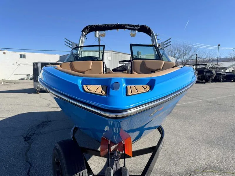 Slide: The Image of 2022 MasterCraft XT23 boat in vibrant blue, parked on a trailer under clear skies. - 4