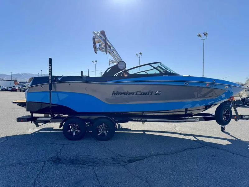 Slide: The Image of 2022 MasterCraft XT23 boat on trailer, blue and black design, parked outdoors. - 5