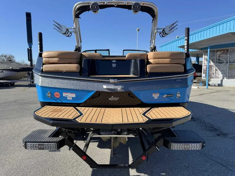 Slide: The Image of 2022 MasterCraft XT23 boat, rear view, blue exterior, tan seats, docked outdoors. - 7