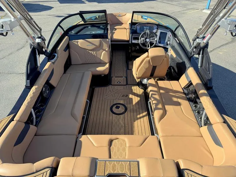 Slide: The Image of 2022 MasterCraft XT23 boat interior with tan seating and modern dashboard. - 9