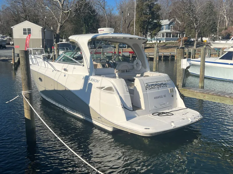 Slide: The Image of 2007 Larson Cabrio 350 boat docked in a marina, surrounded by calm water and trees. - 1