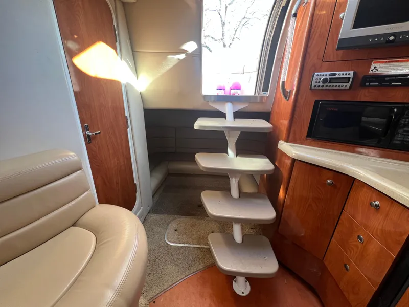 Slide: The Image of Interior of 2007 Larson Cabrio 350 boat with modern wood cabinetry and compact staircase. - 12