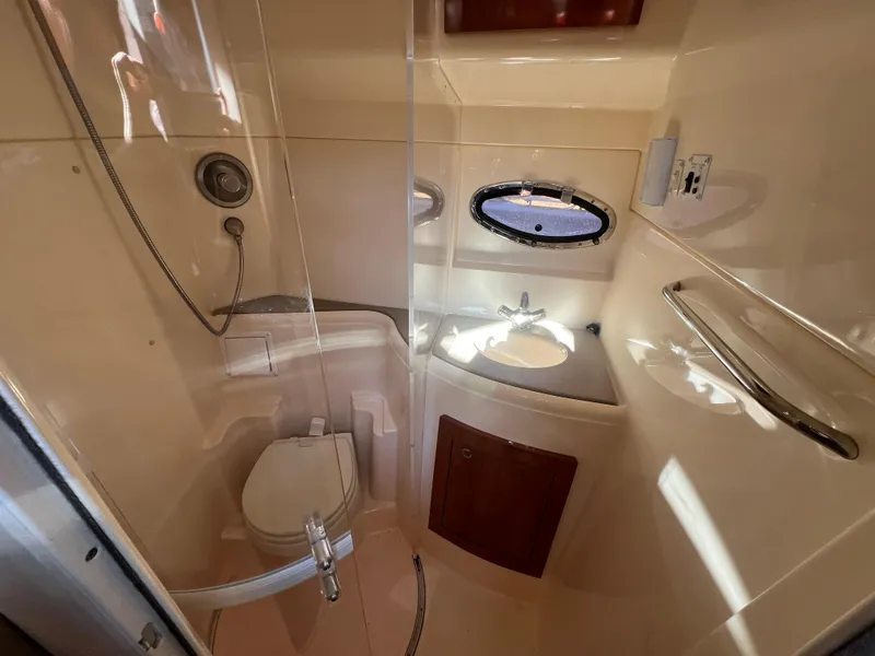 Slide: The Image of 2007 Larson Cabrio 350 boat bathroom with shower, sink, and porthole window. - 16