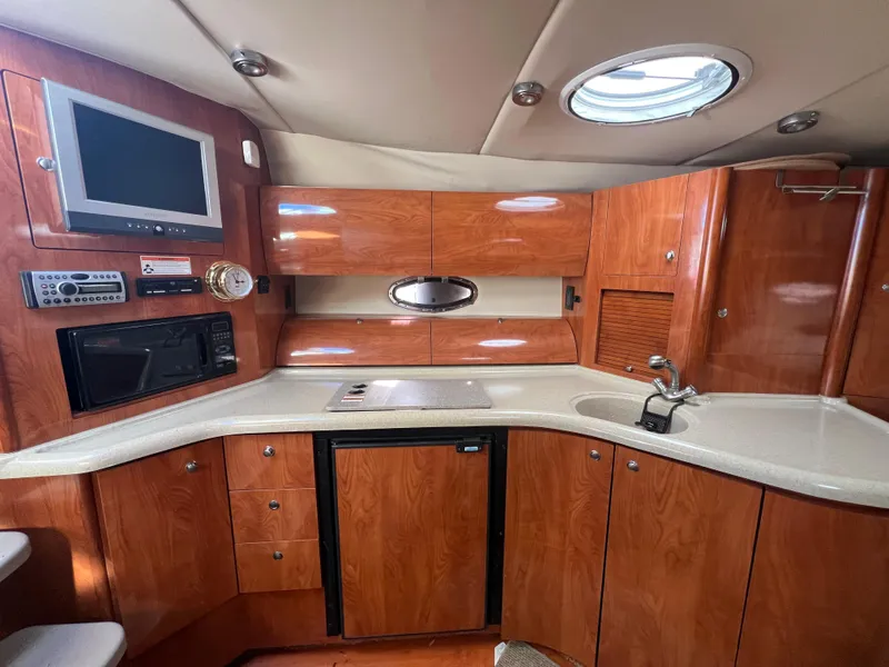 Slide: The Image of 2007 Larson Cabrio 350 yacht interior with wood cabinetry, kitchenette, and modern amenities. - 7