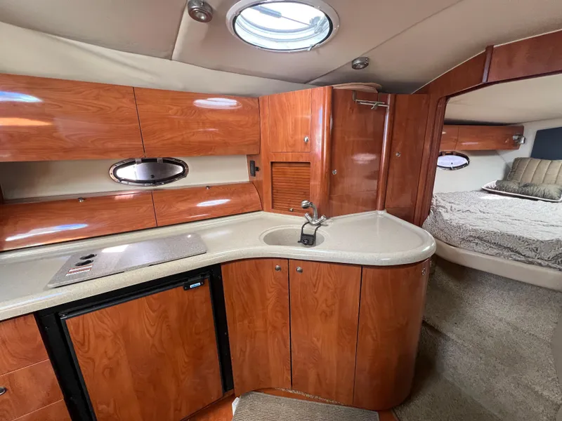 Slide: The Image of 2007 Larson Cabrio 350 interior with wood cabinetry, kitchenette, and cozy sleeping area. - 8