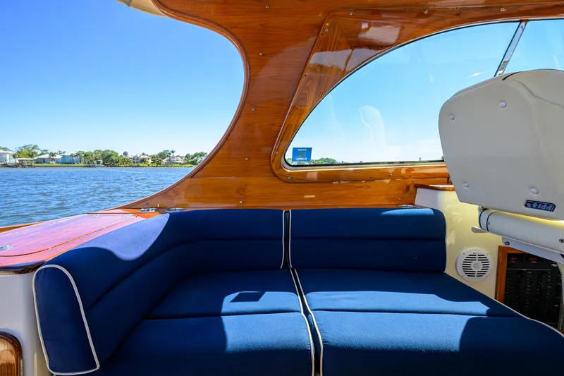 Slide: The Image of Hinckley Picnic Boat 37 MKIII interior with blue seating, wooden accents, and water view. - 10