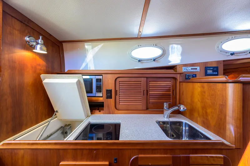 Slide: The Image of Hinckley Picnic Boat 37 MKIII 2010 interior kitchen with sink, stove, and wooden cabinetry. - 18
