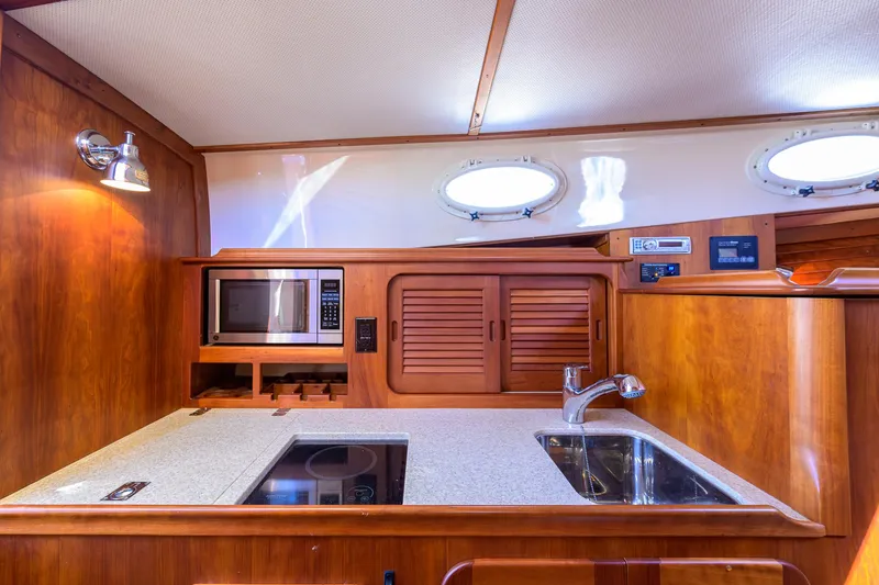 Slide: The Image of 2010 Hinckley Picnic Boat 37 MKIII galley with wood cabinetry, sink, and microwave. - 19