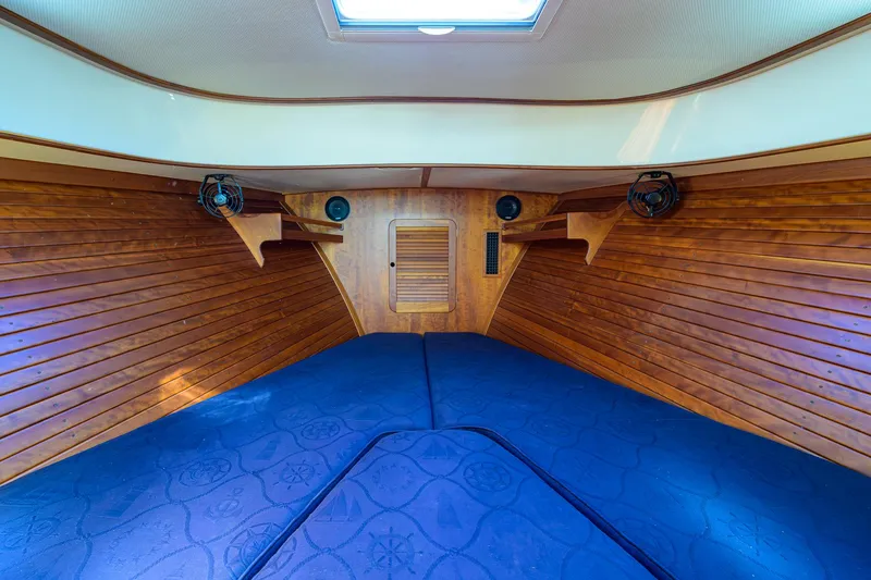 Slide: The Image of 2010 Hinckley Picnic Boat 37 MKIII cabin interior with wooden paneling and blue cushions. - 21
