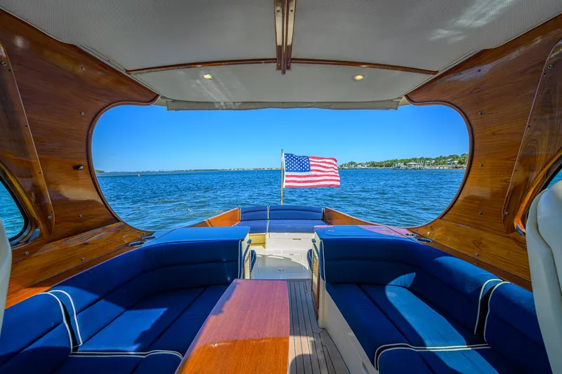 Slide: The Image of Hinckley Picnic Boat 37 MKIII interior with American flag, blue seating, and ocean view. - 9