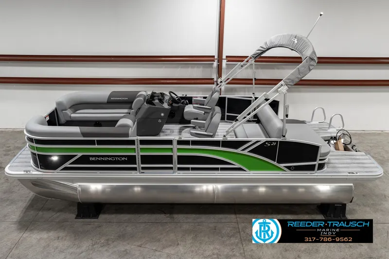 Slide: The Image of 2025 Bennington 21 SSB pontoon boat with green accents in a showroom. - 0