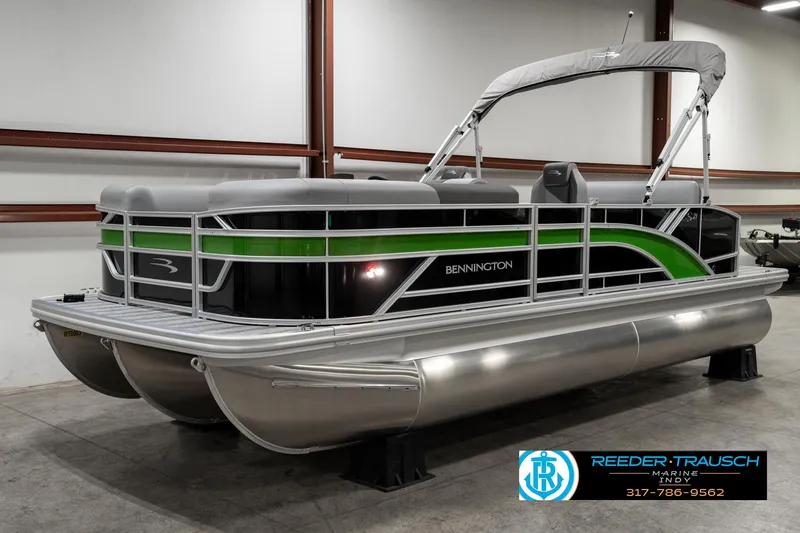 Slide: The Image of 2025 Bennington 21 SSB pontoon boat with green and black accents in a showroom. - 1