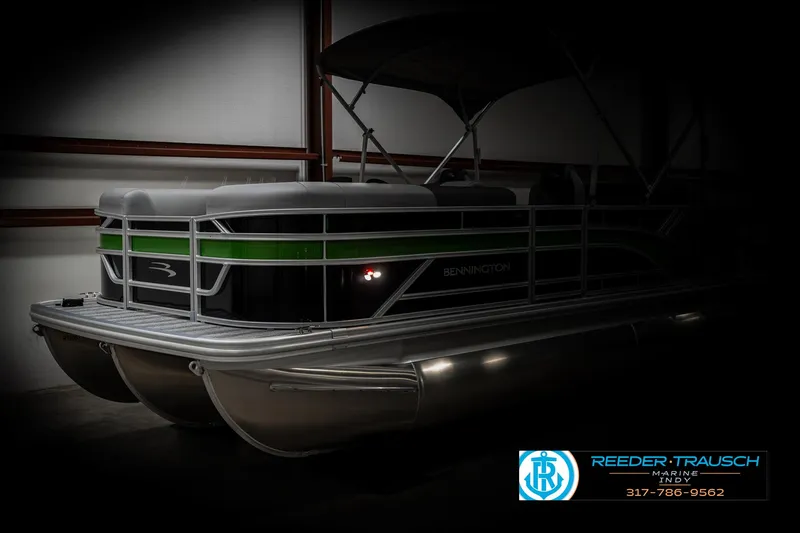 Slide: The Image of 2025 Bennington 21 SSB pontoon boat in a dimly lit showroom. - 3