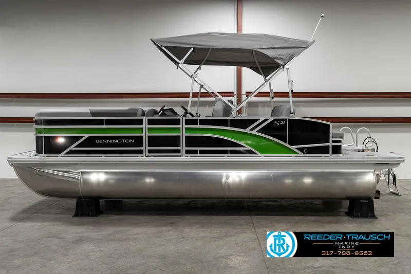 Slide: The Image of 2025 Bennington 21 SSB pontoon boat with green accents and canopy in showroom. - 4