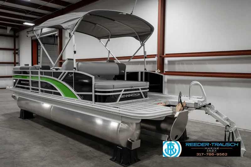 Slide: The Image of 2025 Bennington 21 SSB pontoon boat in a warehouse, featuring sleek design and canopy. - 5