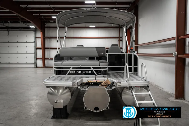 Slide: The Image of 2025 Bennington 21 SSB pontoon boat in a warehouse, rear view with canopy. - 7