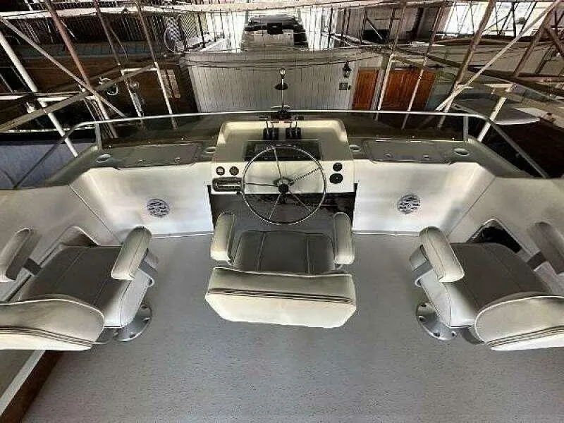 Slide: The Image of 2004 Gibson 50 Houseboat helm with three white captain chairs and steering wheel. - 13
