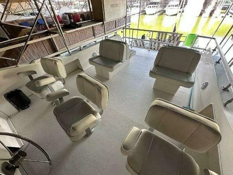 Slide: The Image of 2004 Gibson 50 Houseboat interior with multiple cushioned seats and steering wheel. - 15