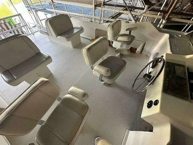 Slide: The Image of 2004 Gibson 50 Houseboat interior with seating and steering wheel in a spacious layout. - 16