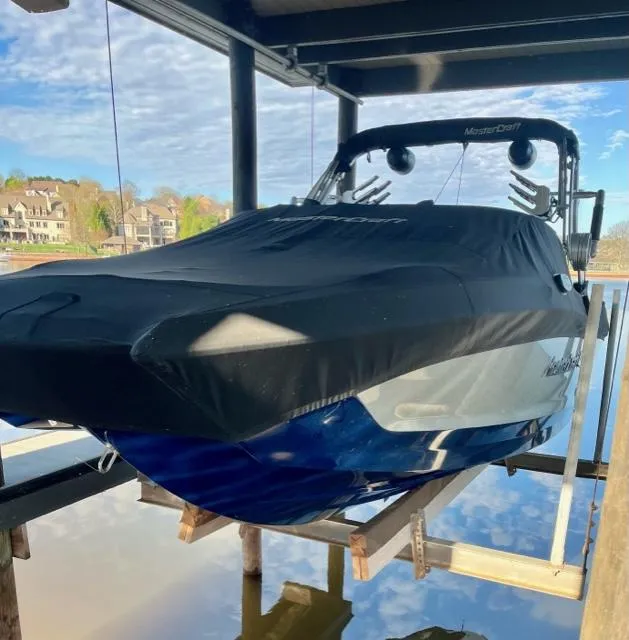 Slide: The Image of 2019 MasterCraft X22 boat covered and docked on a lift by the water. - 15
