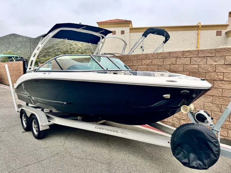 Slide: The Image of 2021 Chaparral 21 SSi boat on trailer, parked outdoors, with a mountainous backdrop. - 1