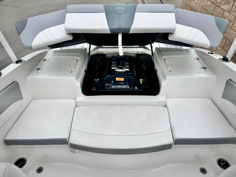 Slide: The Image of 2021 Chaparral 21 SSi boat engine compartment with open hatch, showcasing sleek white seating. - 19