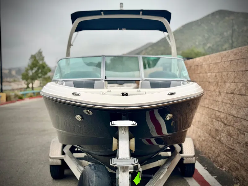 Slide: The Image of 2021 Chaparral 21 SSi boat on trailer, parked near a stone wall. - 2