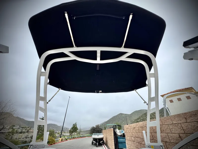 Slide: The Image of 2021 Chaparral 21 SSi boat with black canopy, parked near mountains. - 25
