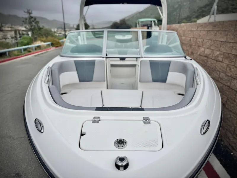Slide: The Image of 2021 Chaparral 21 SSi boat, front view, parked on a road with scenic background. - 9