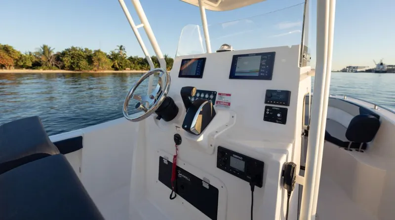 Slide: The Image of 2024 SeaWell 240CC boat dashboard with steering wheel and navigation screens on calm water. - 21