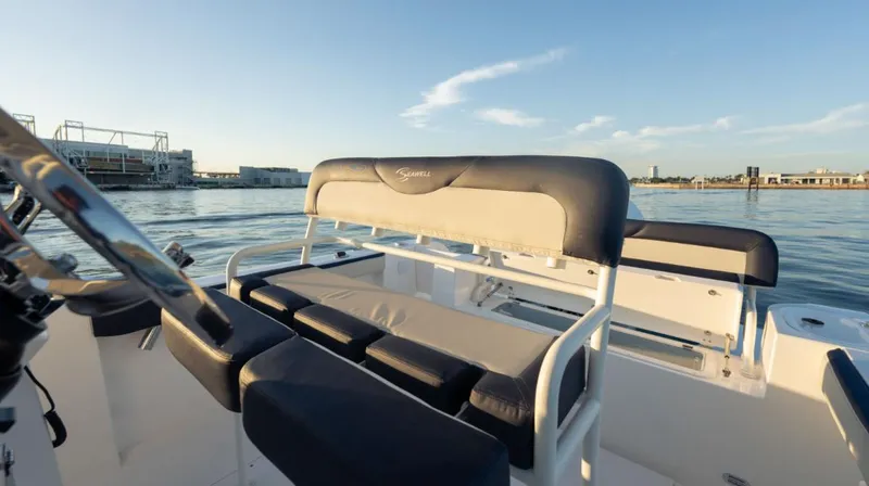 Slide: The Image of 2024 SeaWell 240CC boat interior with cushioned seating, overlooking calm waters and distant shoreline. - 23