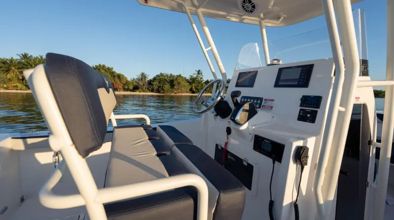 Slide: The Image of 2024 SeaWell 240CC boat interior with modern controls, steering wheel, and seating, near a scenic shoreline. - 24